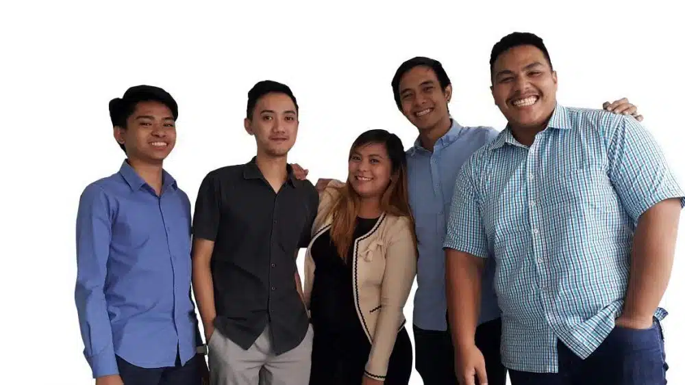 Five colleagues standing together and smiling at the camera