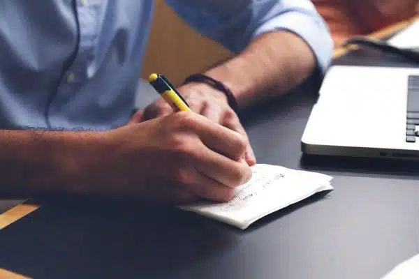 In an office environment, a man in a suit is diligently taking notes at his desk