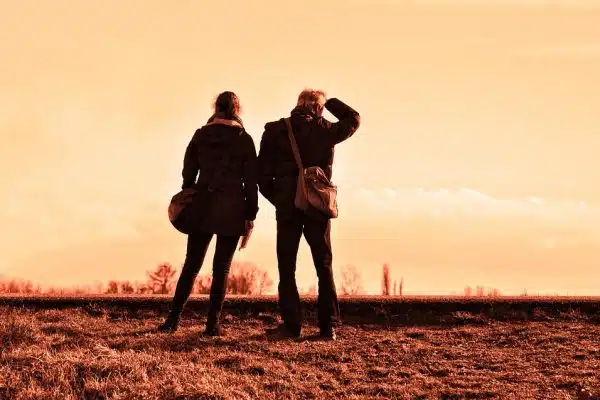 Two individuals are standing at the side of the road.