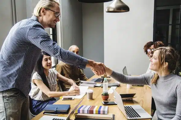 Man and woman shaking hands in an office, highlighting a successful agreement or partnership.