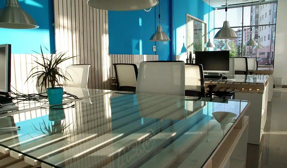 Office space featuring a glass table and walls with a touch of blue.