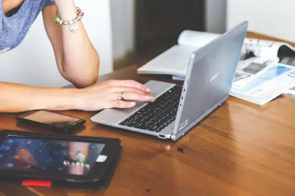 Woman working on her laptop, with her tablet placed next to her.