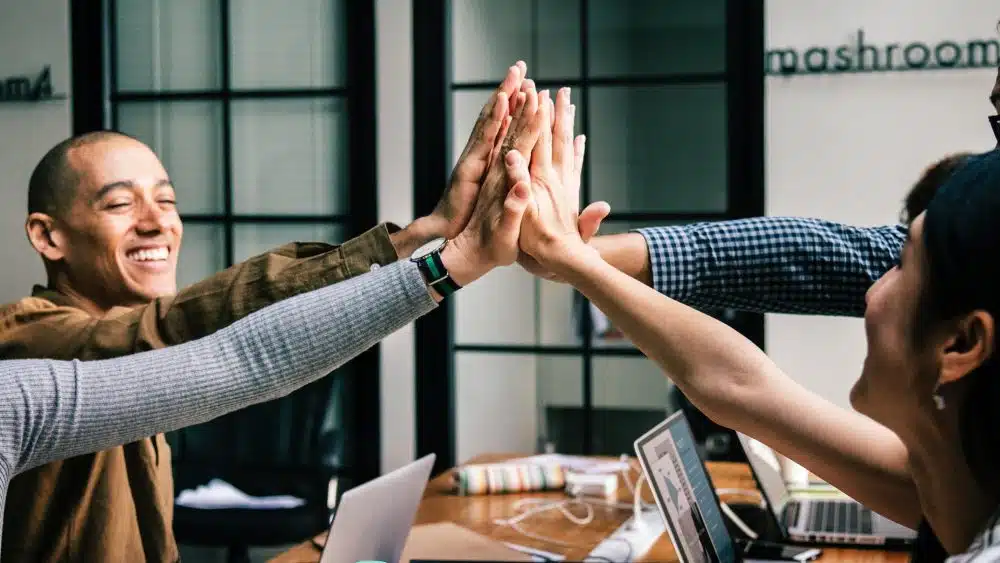 Group of colleagues joyfully celebrating with high-fives