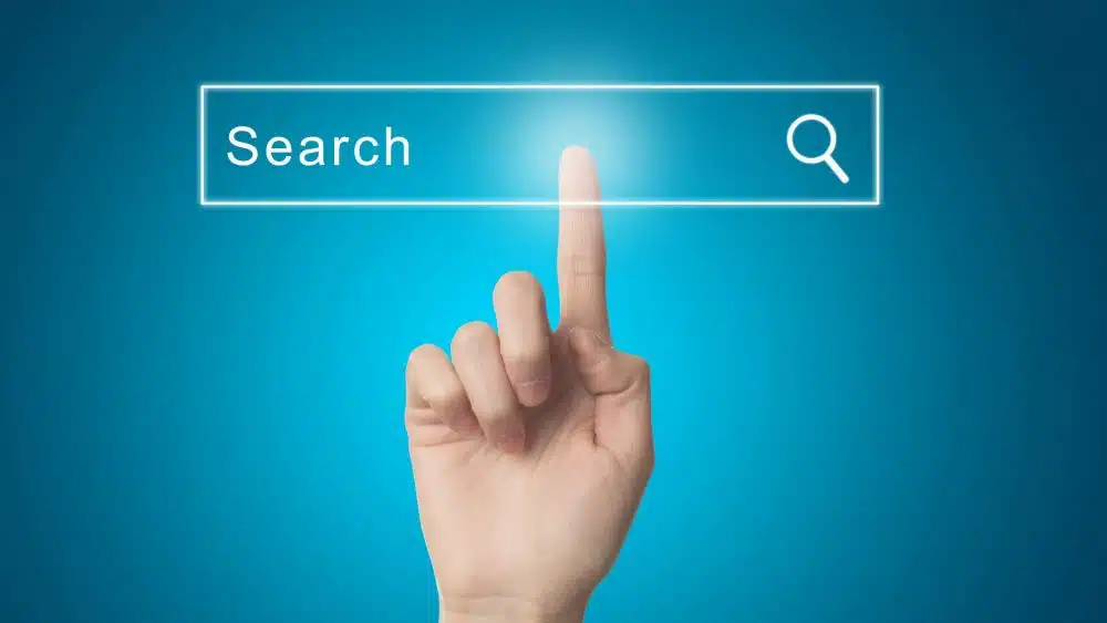 A finger pressing a digital search bar on a blue background, with the word 'Search' inside the bar